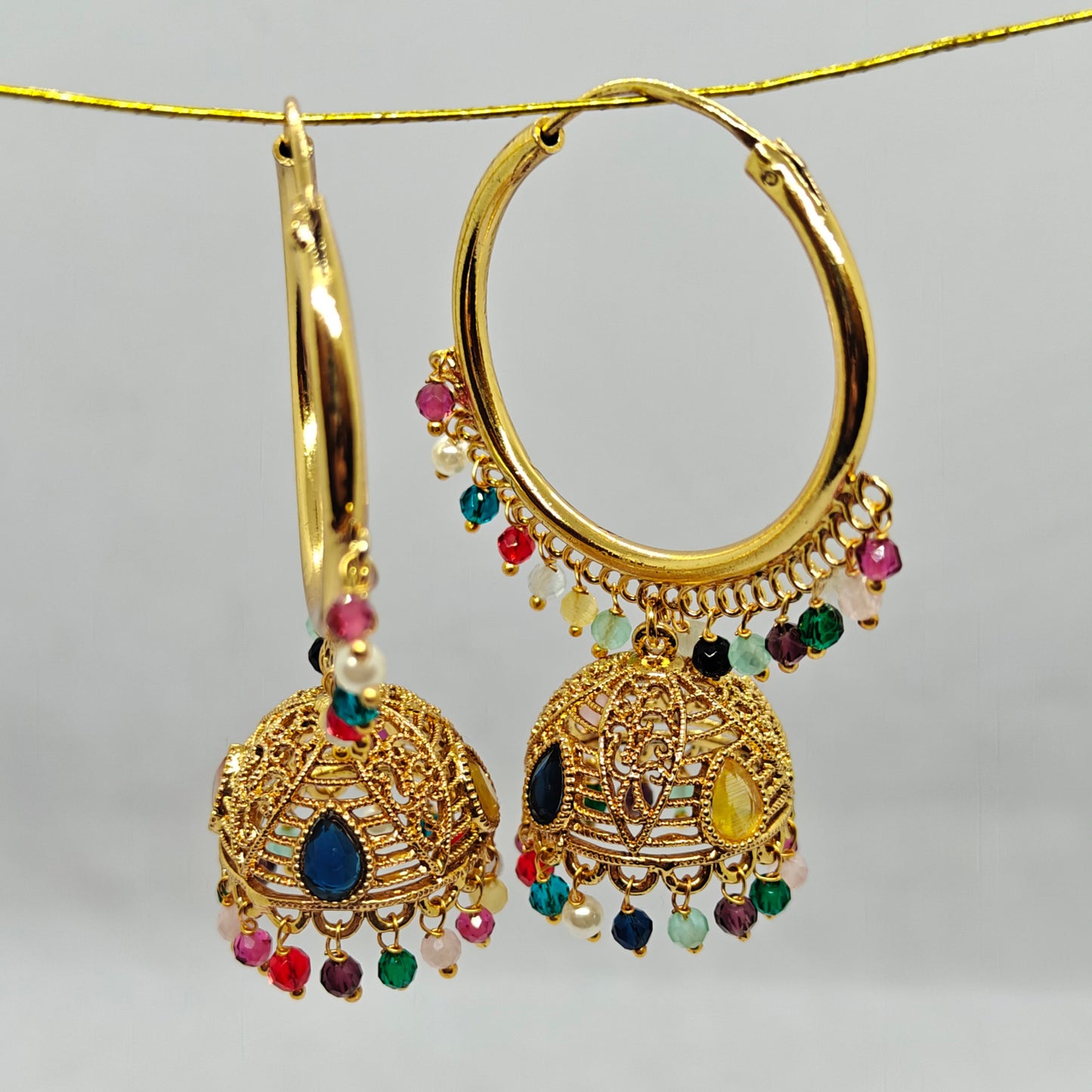Gold hoop earrings with colorful beads on a Grey background 