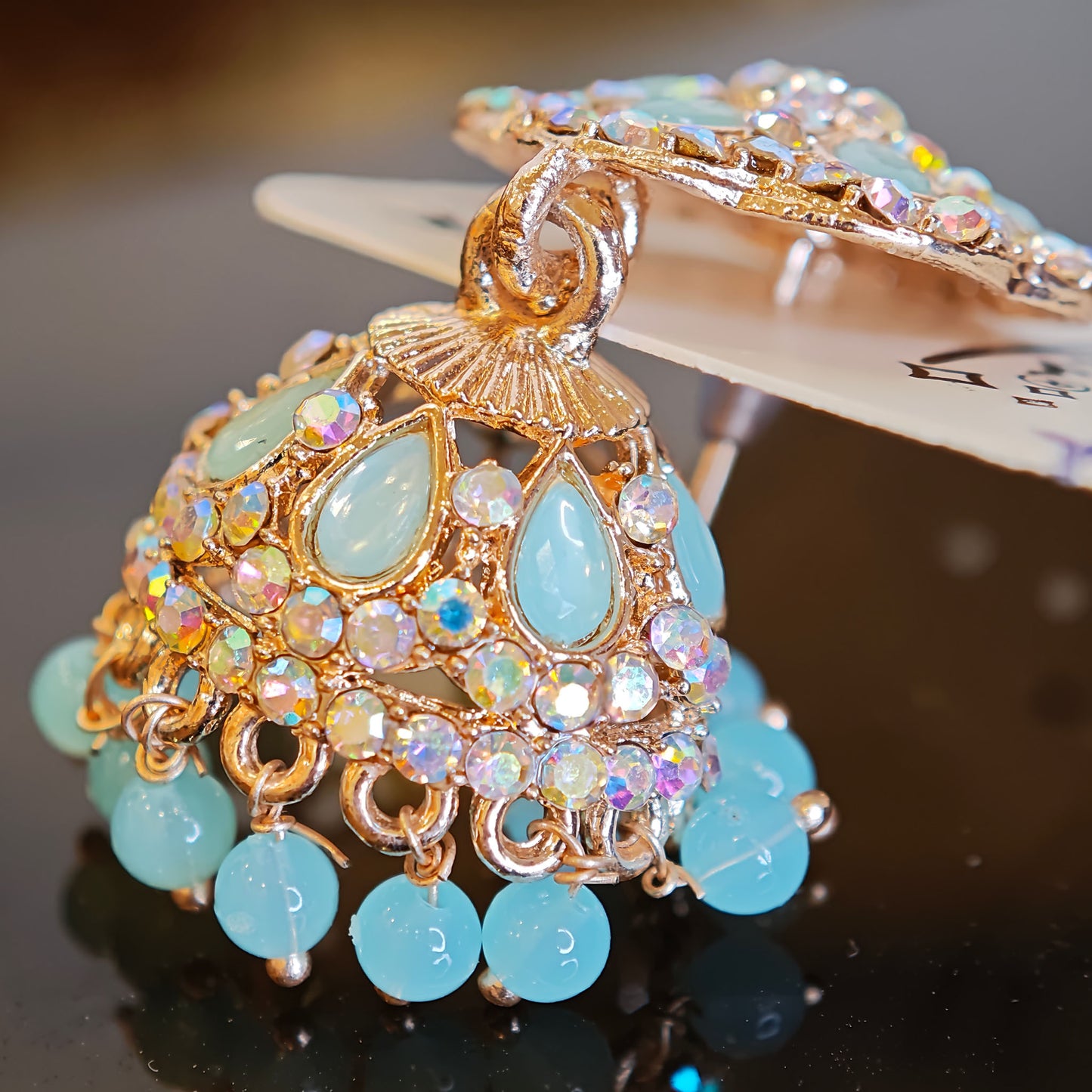 Decorative bell with turquoise stones and gold accents on a dark surface