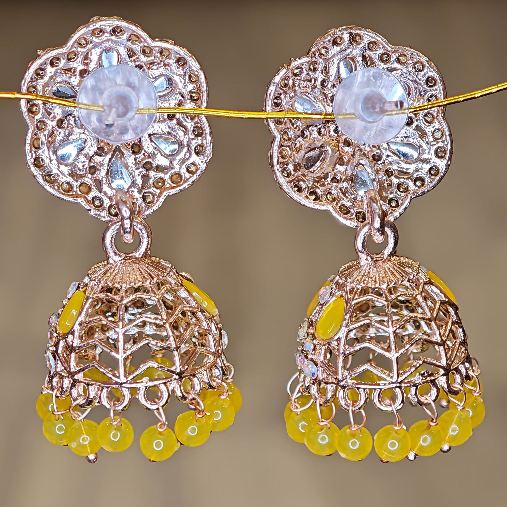 Decorative earrings with floral top and jhumka design on a blurred background