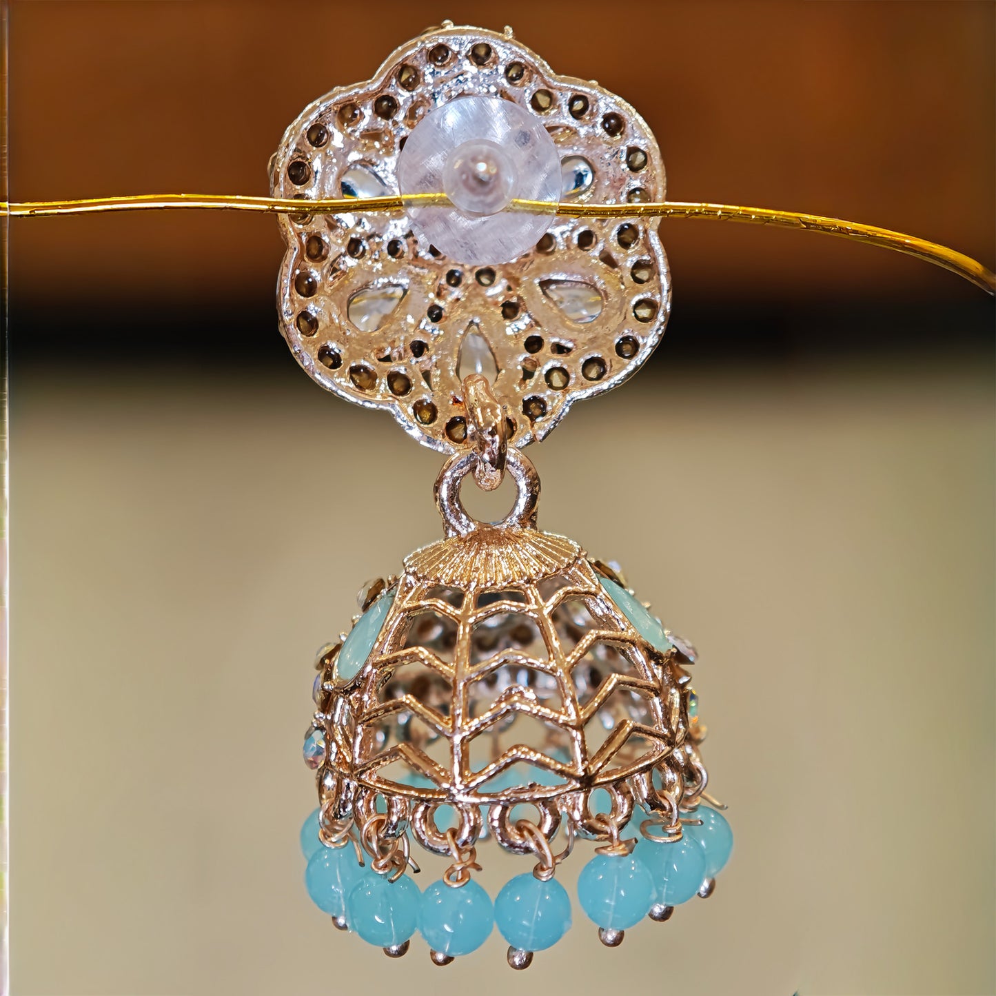Back view of Earrings with gold and turquoise elements on a blurred background