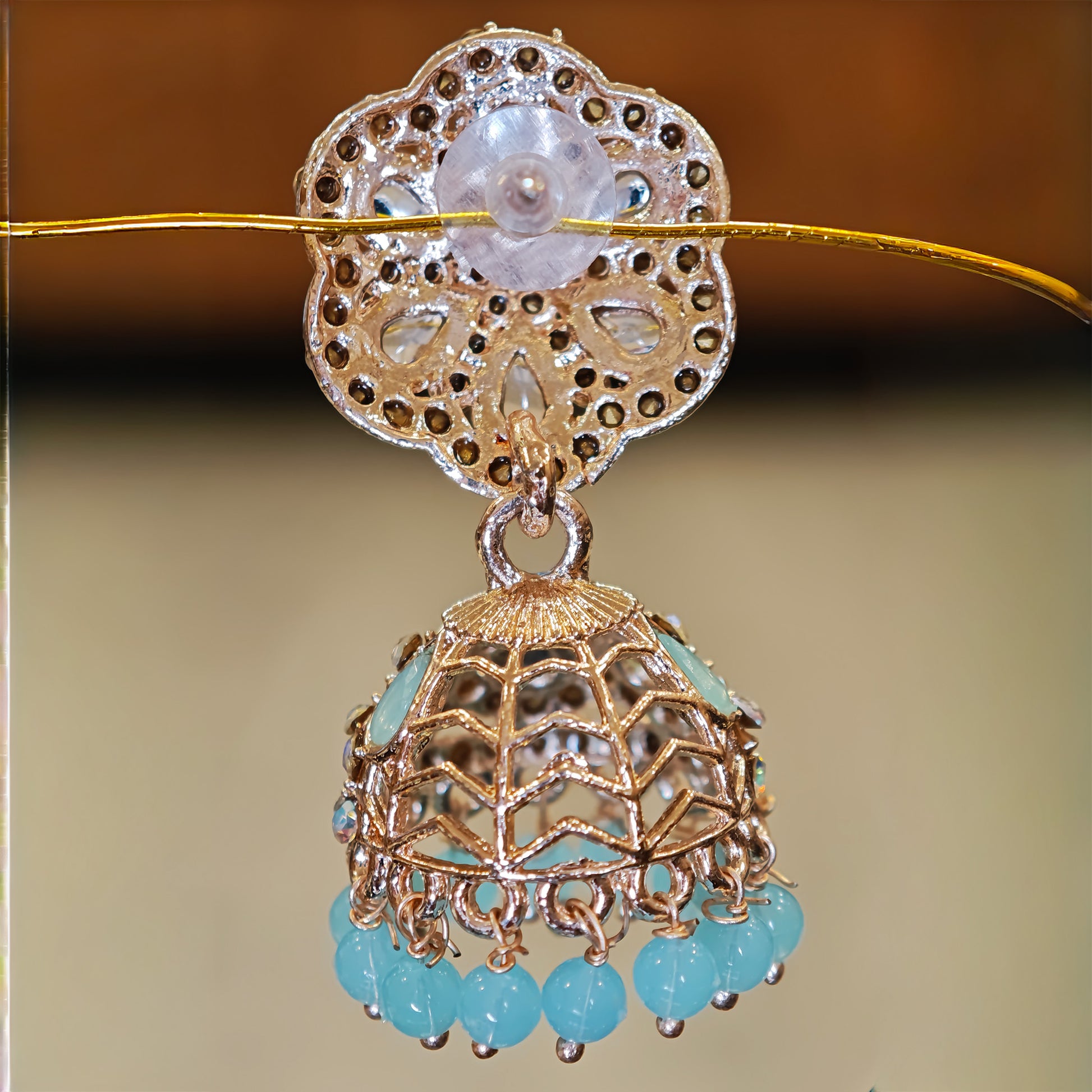 Back view of Earrings with gold and turquoise elements on a blurred background