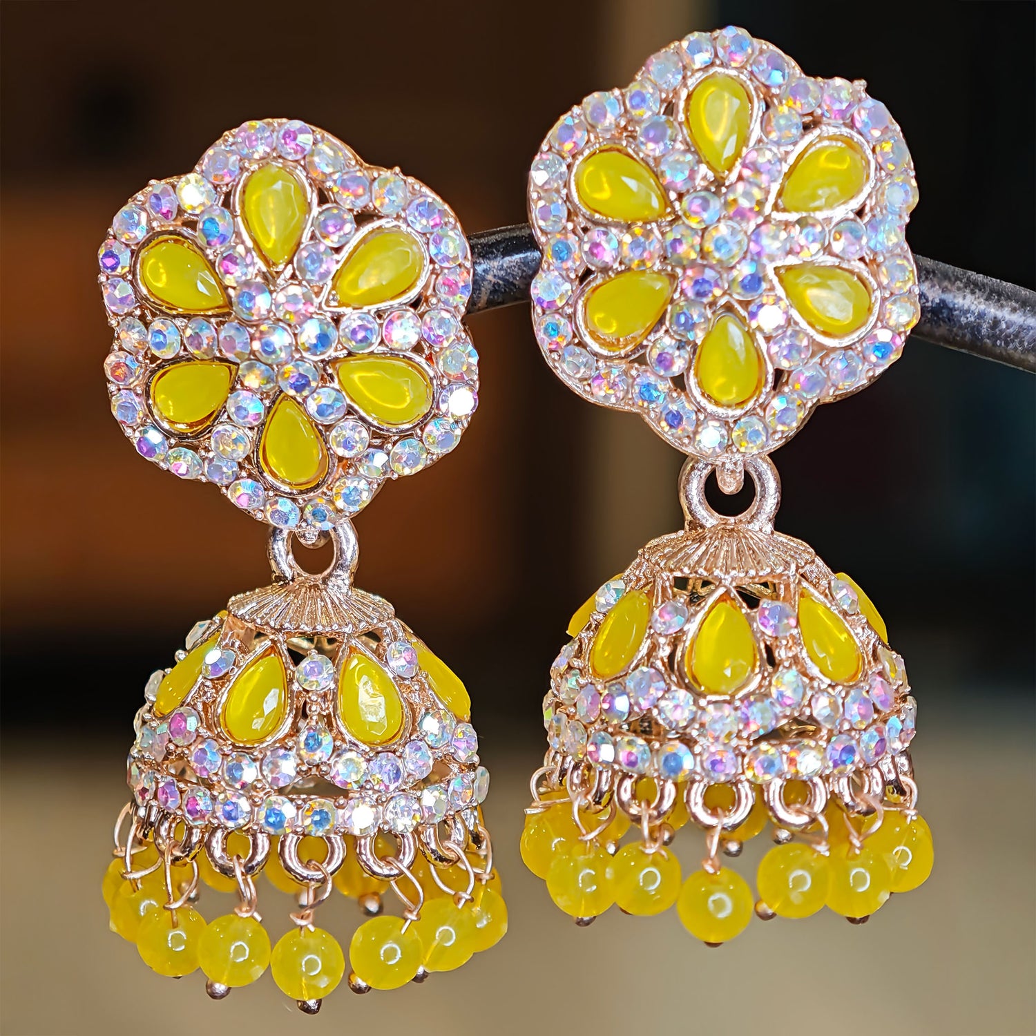 Pair of ornate earrings with yellow stones and intricate designs on a blurred background